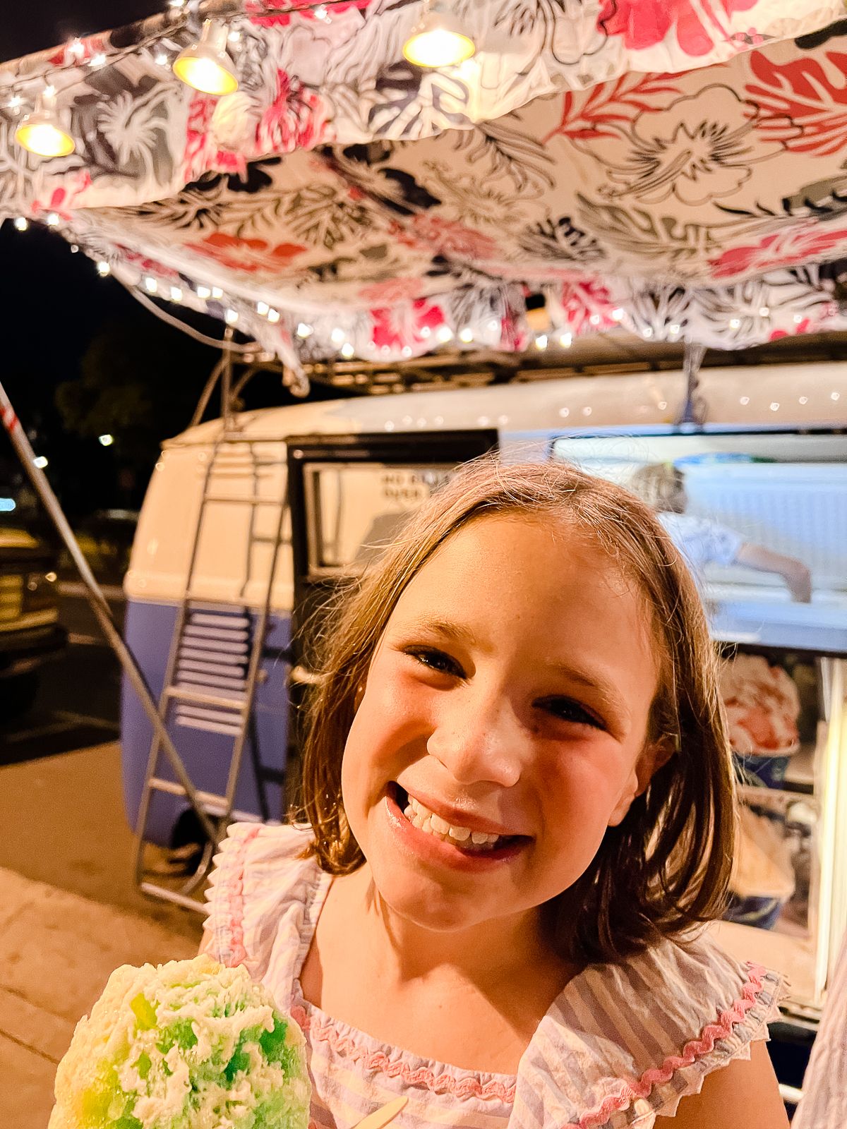 a smiling little girl in front of a VW shave ice truck in Maui