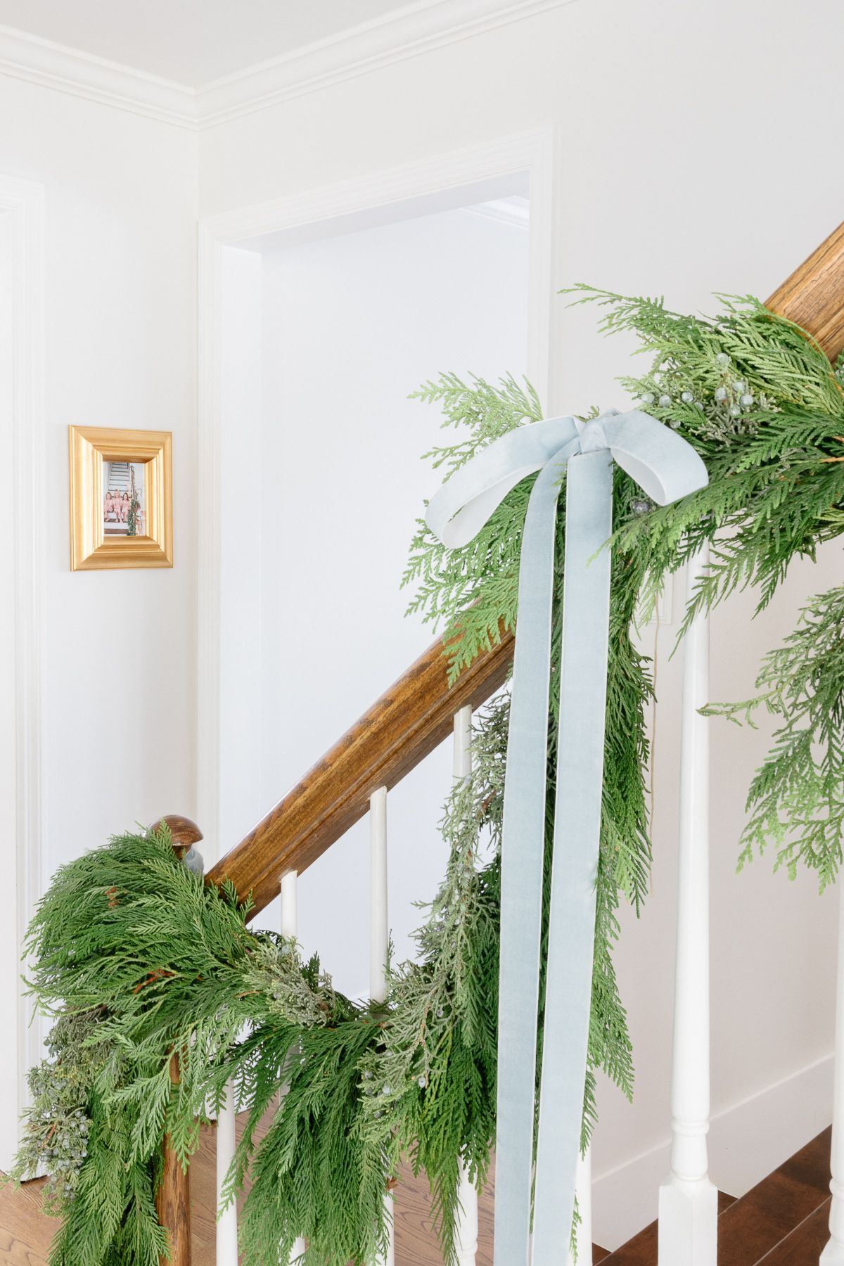 Fresh greenery garland on a wooden staircase for a minimalist Christmas decor idea