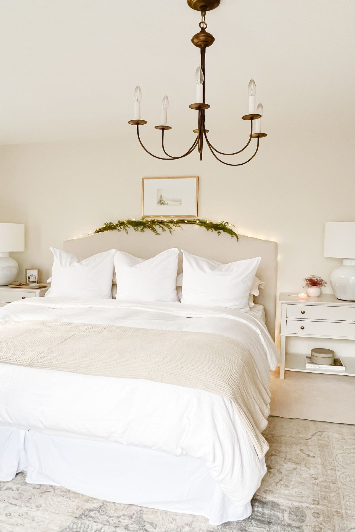 A bedroom decorated with a minimalist Christmas style with a faux greenery garland over the headboard