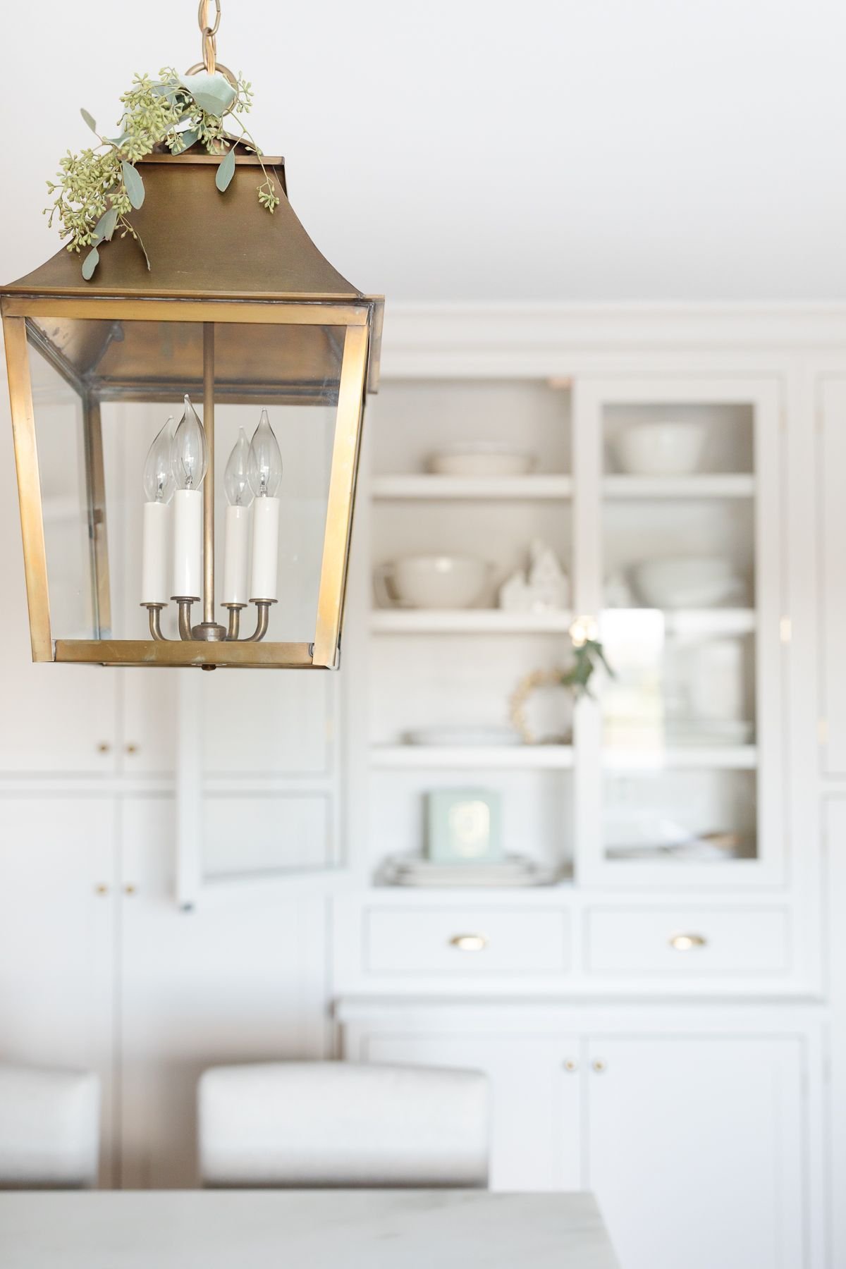 A white kitchen with a brass lantern, decorated in a minimalist Christmas style
