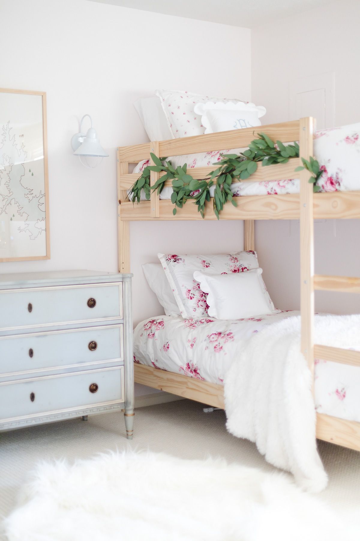 A wood bunk bedroom with a garland on the top bunk
