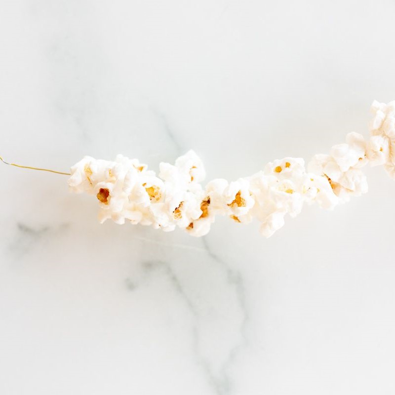 A garland of popcorn on a white marble surface.