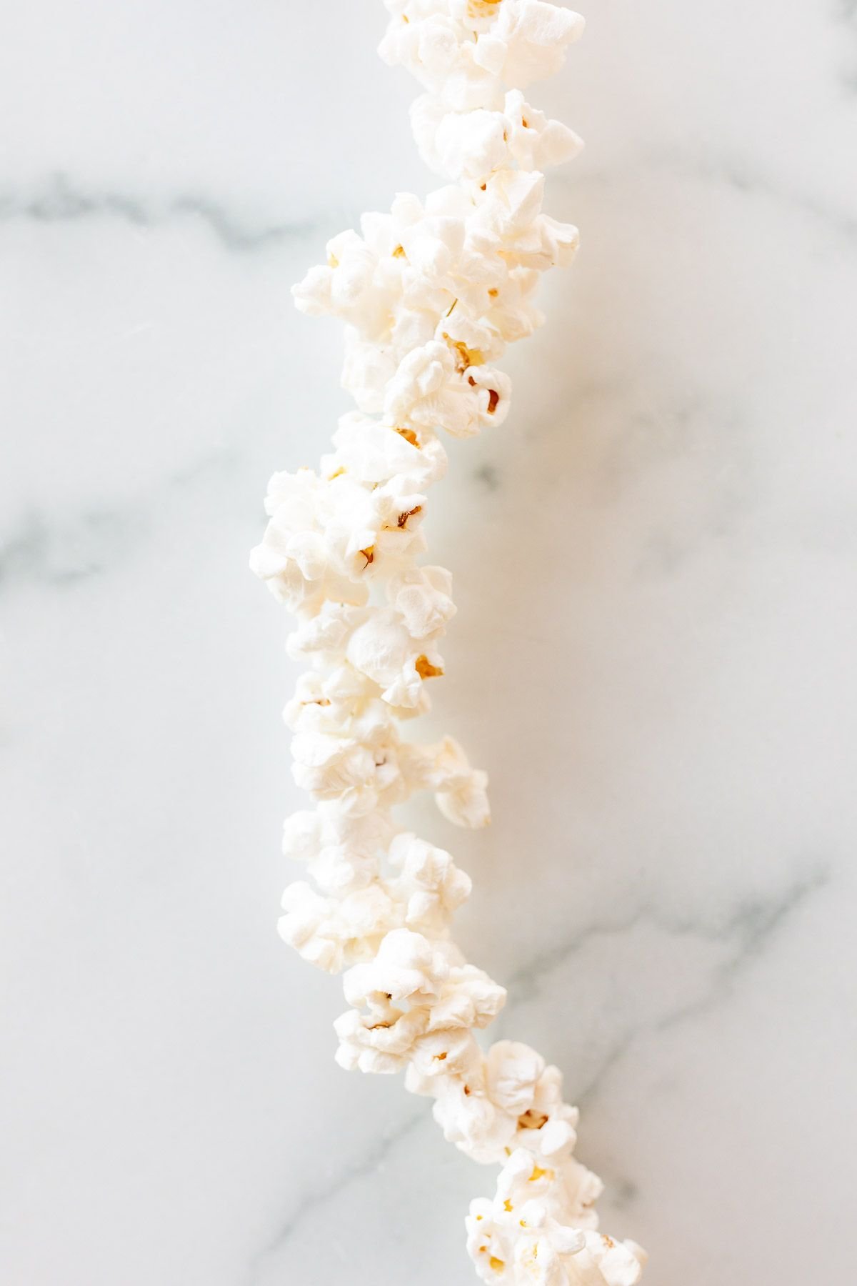 Serangkaian garland popcorn di atas permukaan marmer putih.