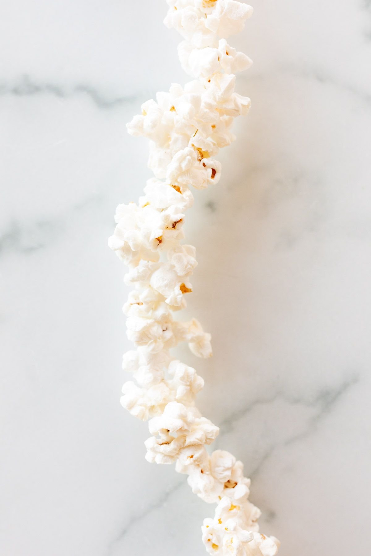 A string of popcorn garland on a white marble surface.