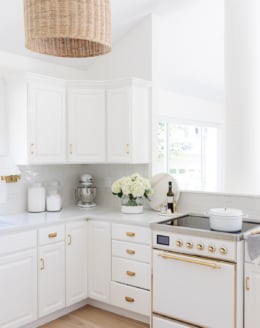 off white kitchen with brass hardware and rattan pendant