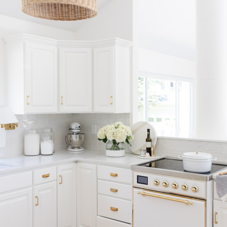 off white kitchen with brass hardware and rattan pendant