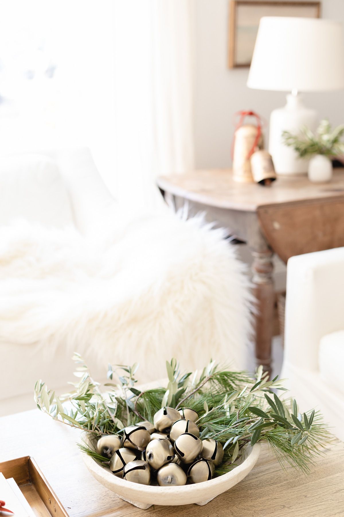 A bowl of greenery and jingle bells on a wooden coffee table