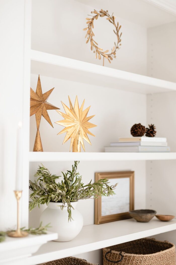 Gold stars and a gold wreath for traditional Christmas decorating on white shelves