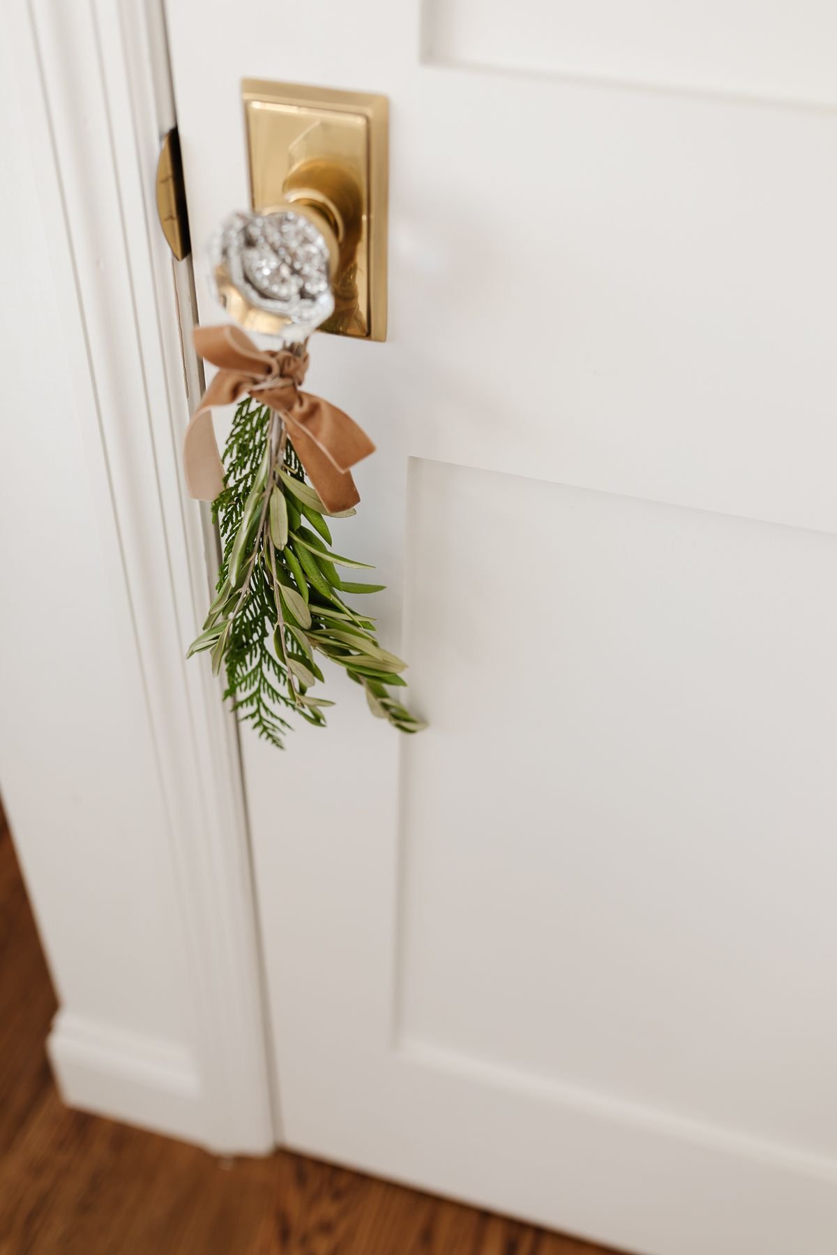 greenery tied onto a brass doorknob with a velvet ribbon