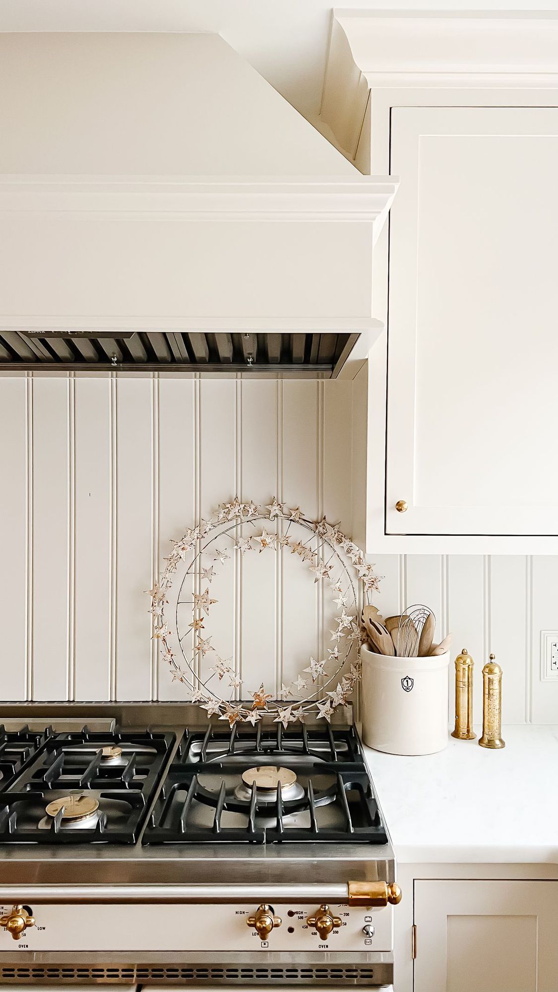 A wreath of metal stars leaning against a backsplash in a cream-colored kitchen