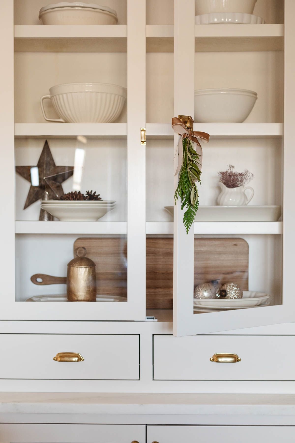 Traditional Christmas decorating, with gold stars and bells behind a glass cabinet