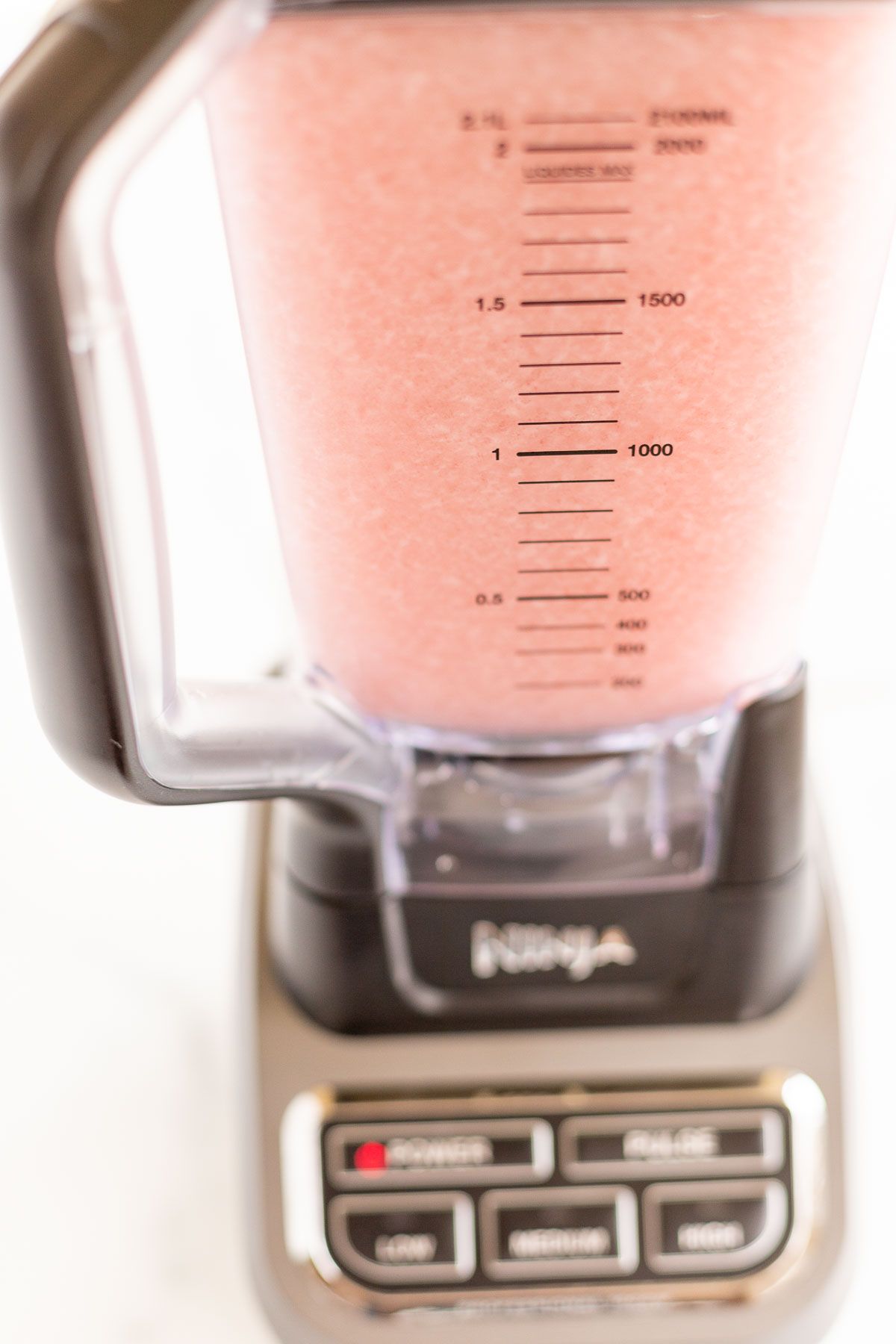 A blender full of a pink frozen concoction of White Christmas margaritas