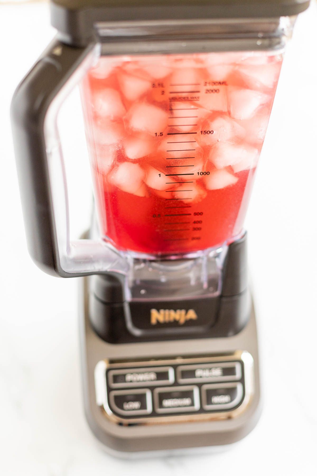 A Ninja blender full of ice and cranberry margarita ingredients