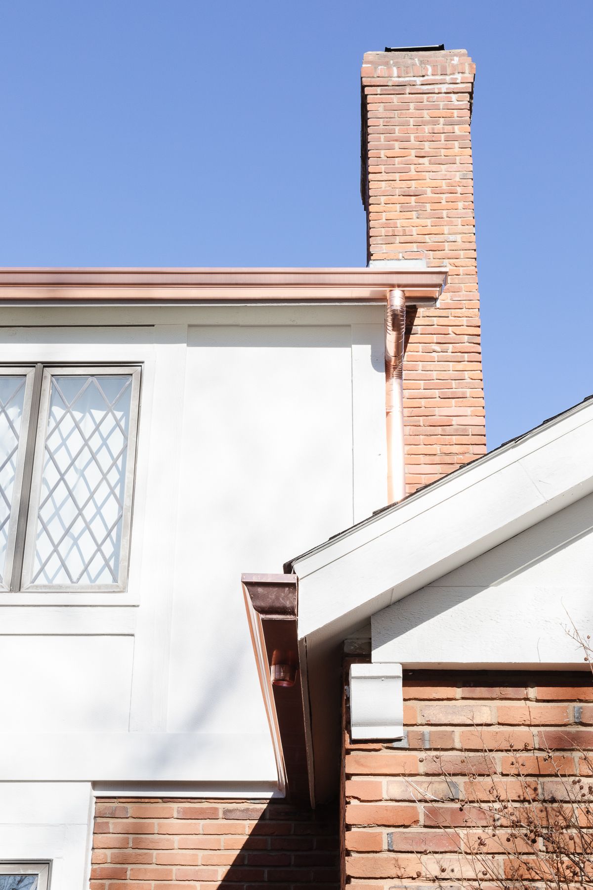 Copper gutters on a white and brick home