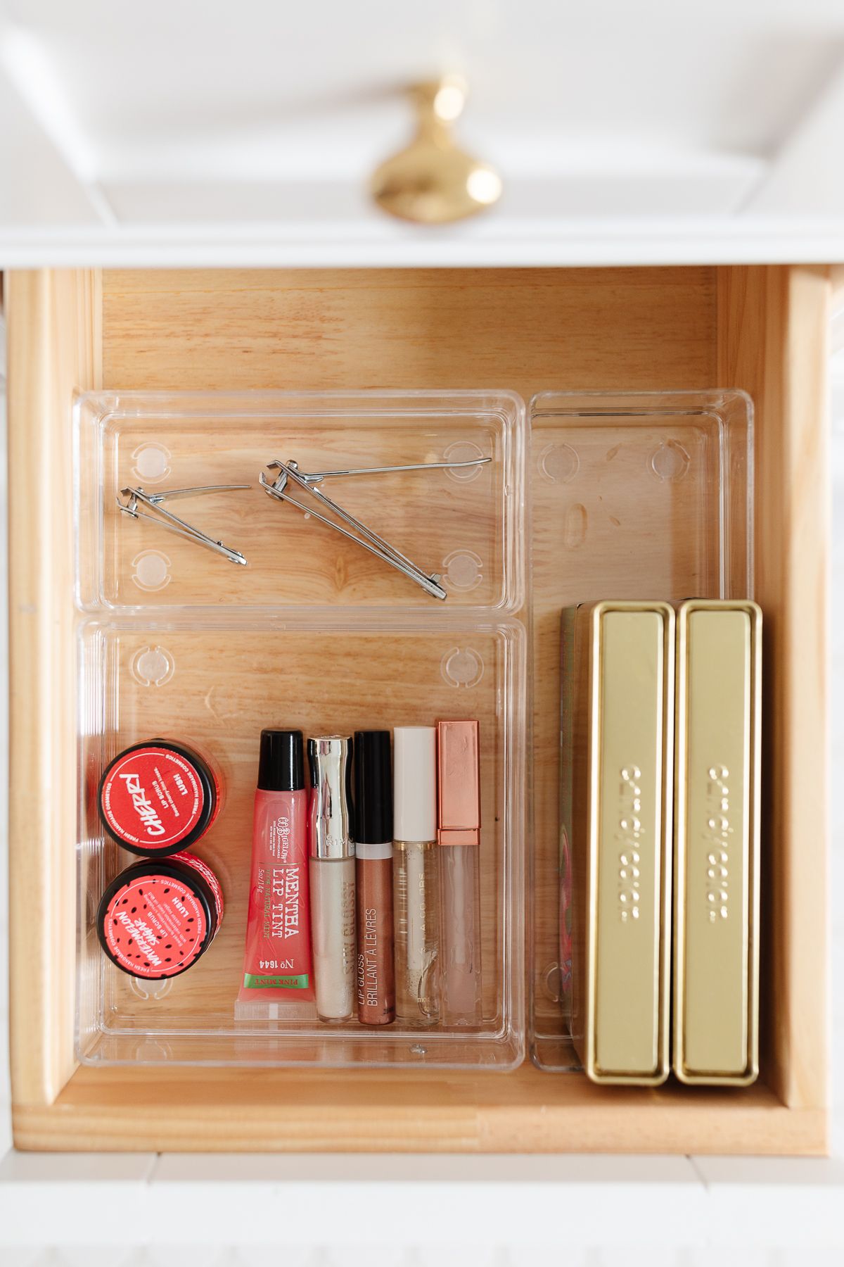 A clear plastic bathroom drawer organizer with make up