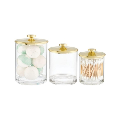Bathroom organization made easy with three glass jars featuring gold lids for your bathroom drawer. Includes cotton swabs for added convenience.