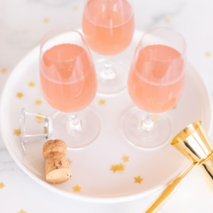 3 glasses of champagne margaritas on a white tray, gold confetti surrounding