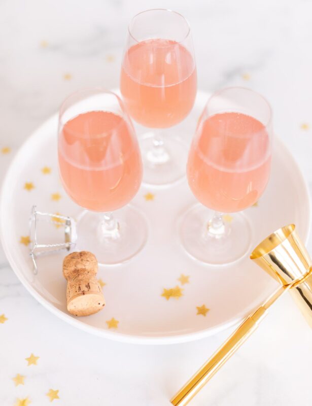 3 glasses of champagne margaritas on a white tray, gold confetti surrounding