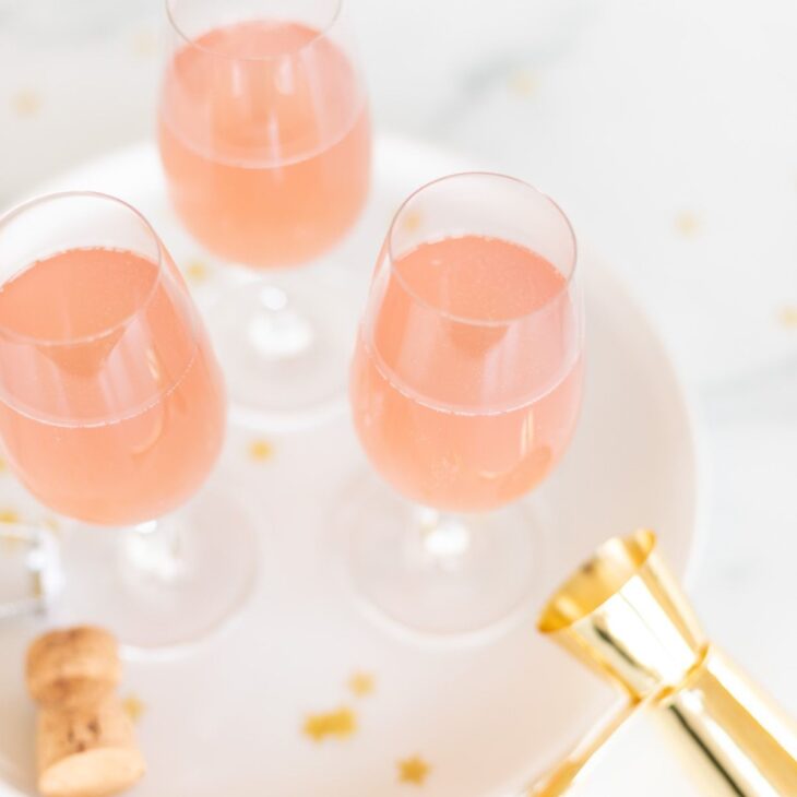 3 glasses of pink champagne margaritas on a white tray with gold confetti surrounding