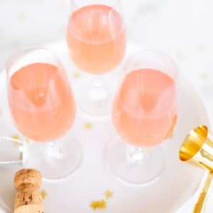 3 glasses of pink champagne margaritas on a white tray with gold confetti surrounding