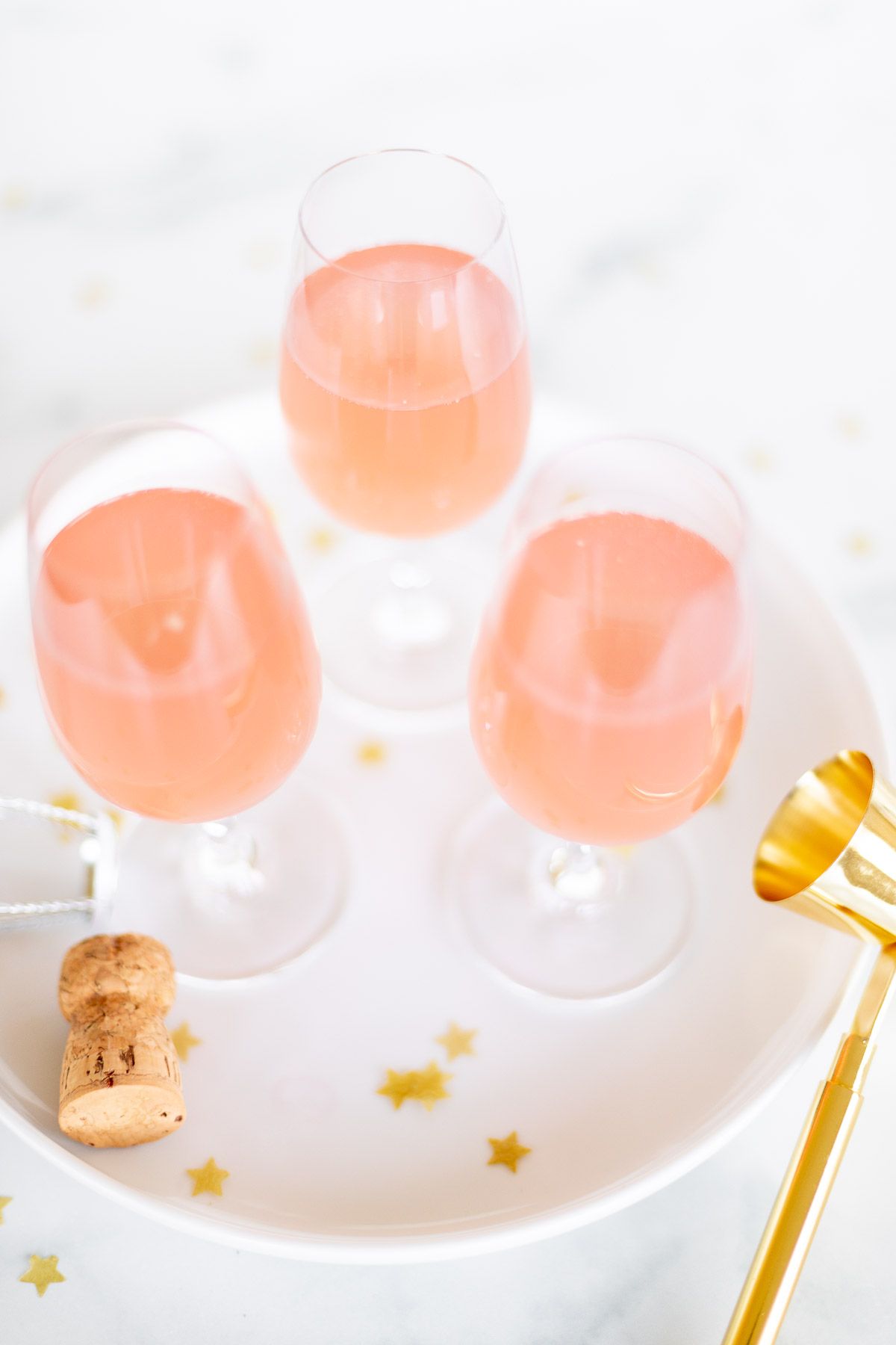 3 glasses of pink champagne margaritas on a white tray with gold confetti surrounding