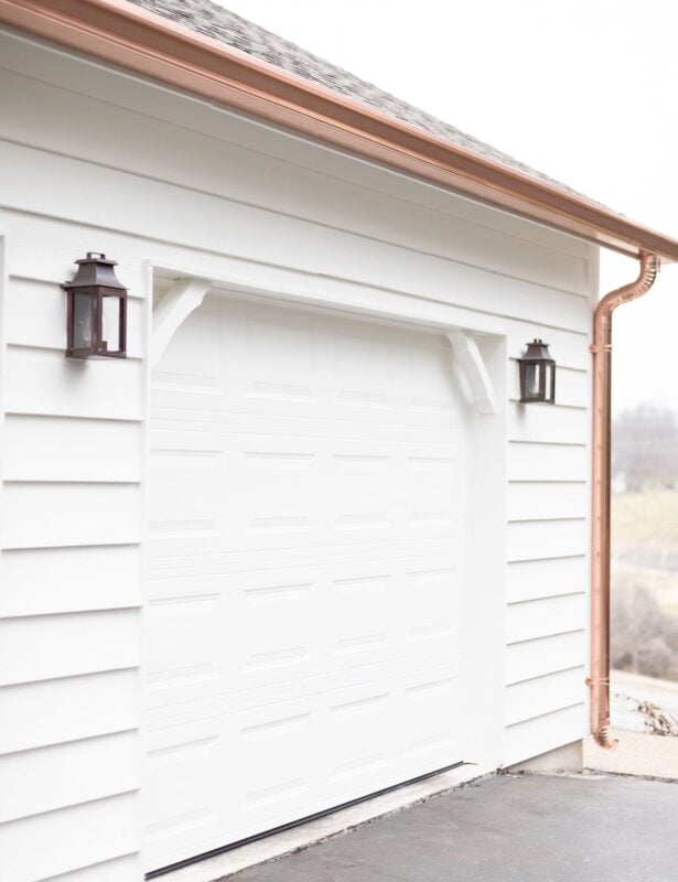 Copper gutters and copper downspouts running over a white exterior garage