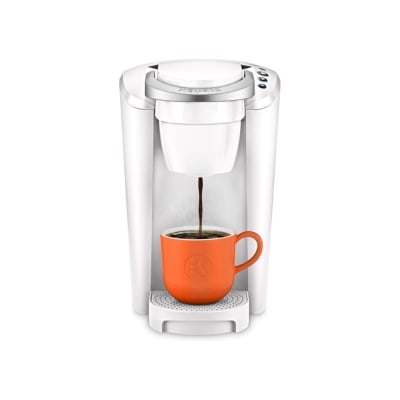 An orange keurig coffee maker with a cup.