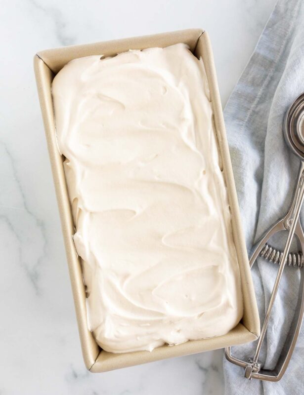 A gold loaf pan filled with homemade mascarpone ice cream, scoop to the side