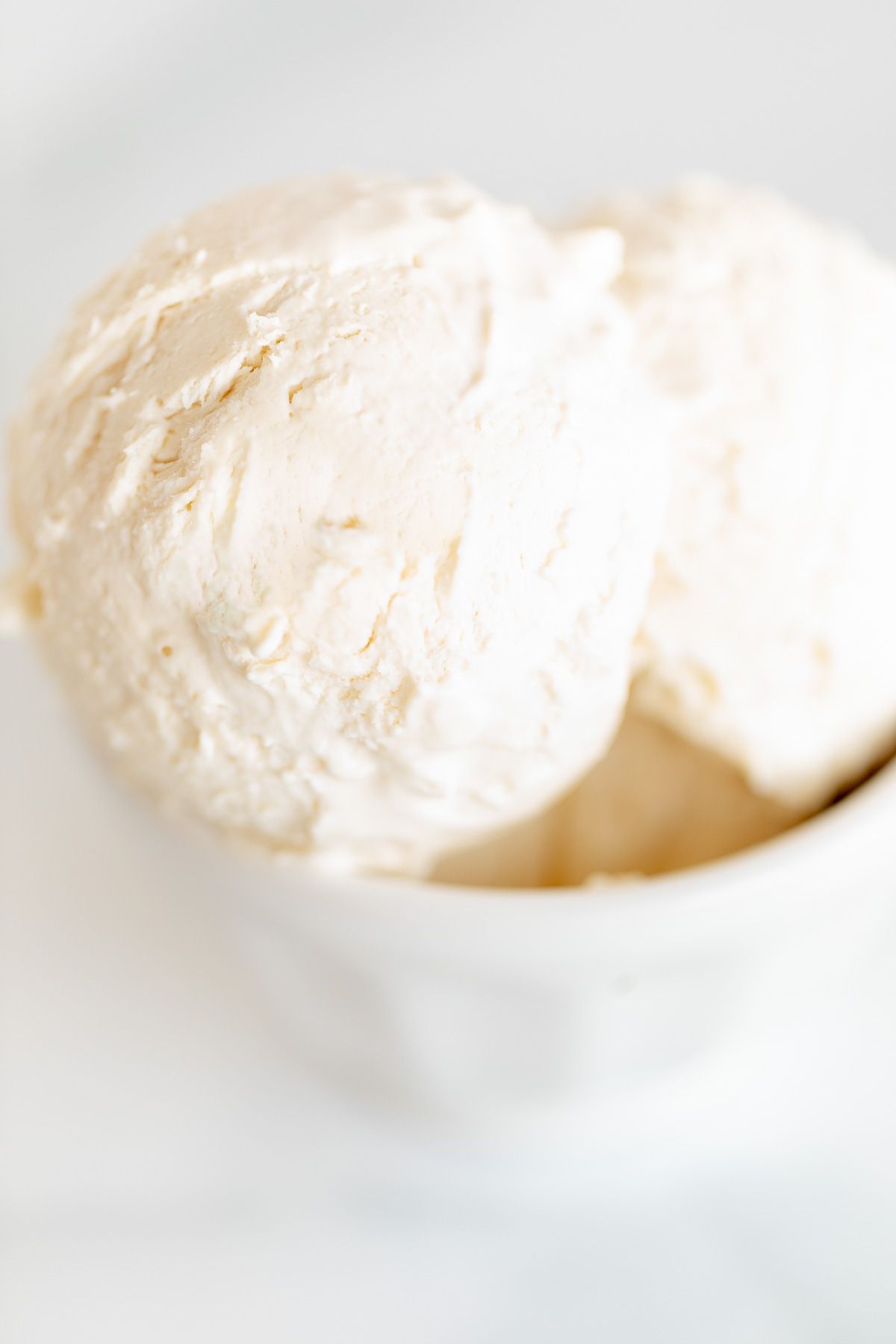 A white bowl on a marble surface, filled with frozen mascarpone ice cream