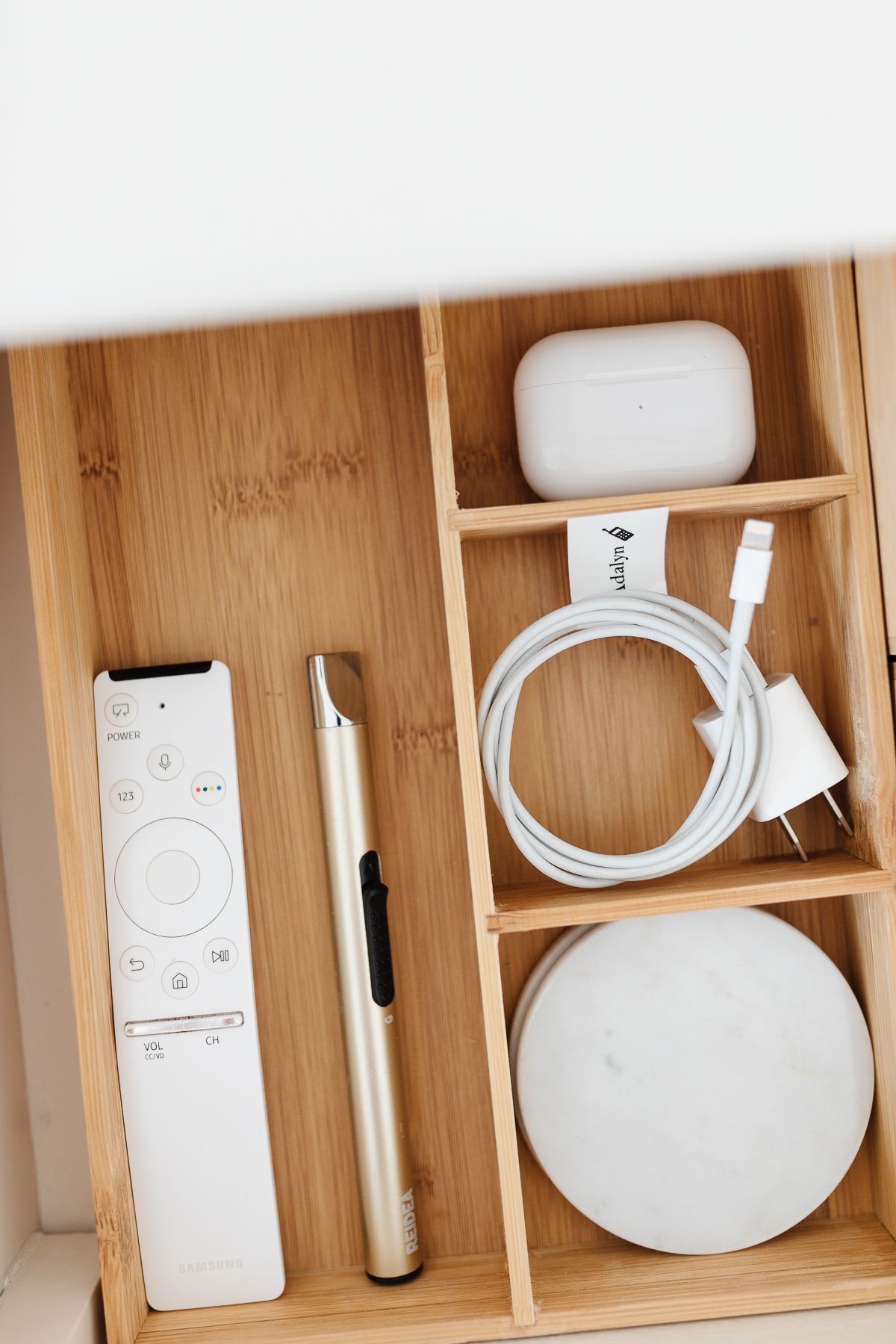 An open drawer with nightstand organization of remotes, lotions and more