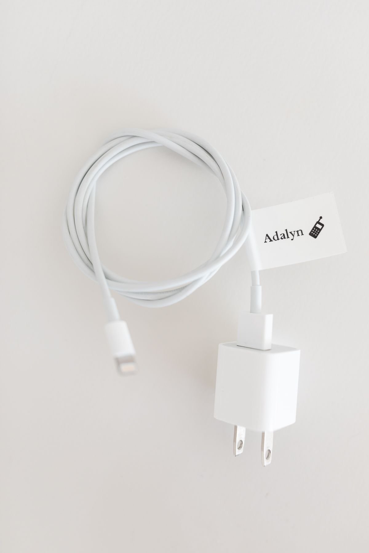 A white phone charger cord with a label for nightstand organization