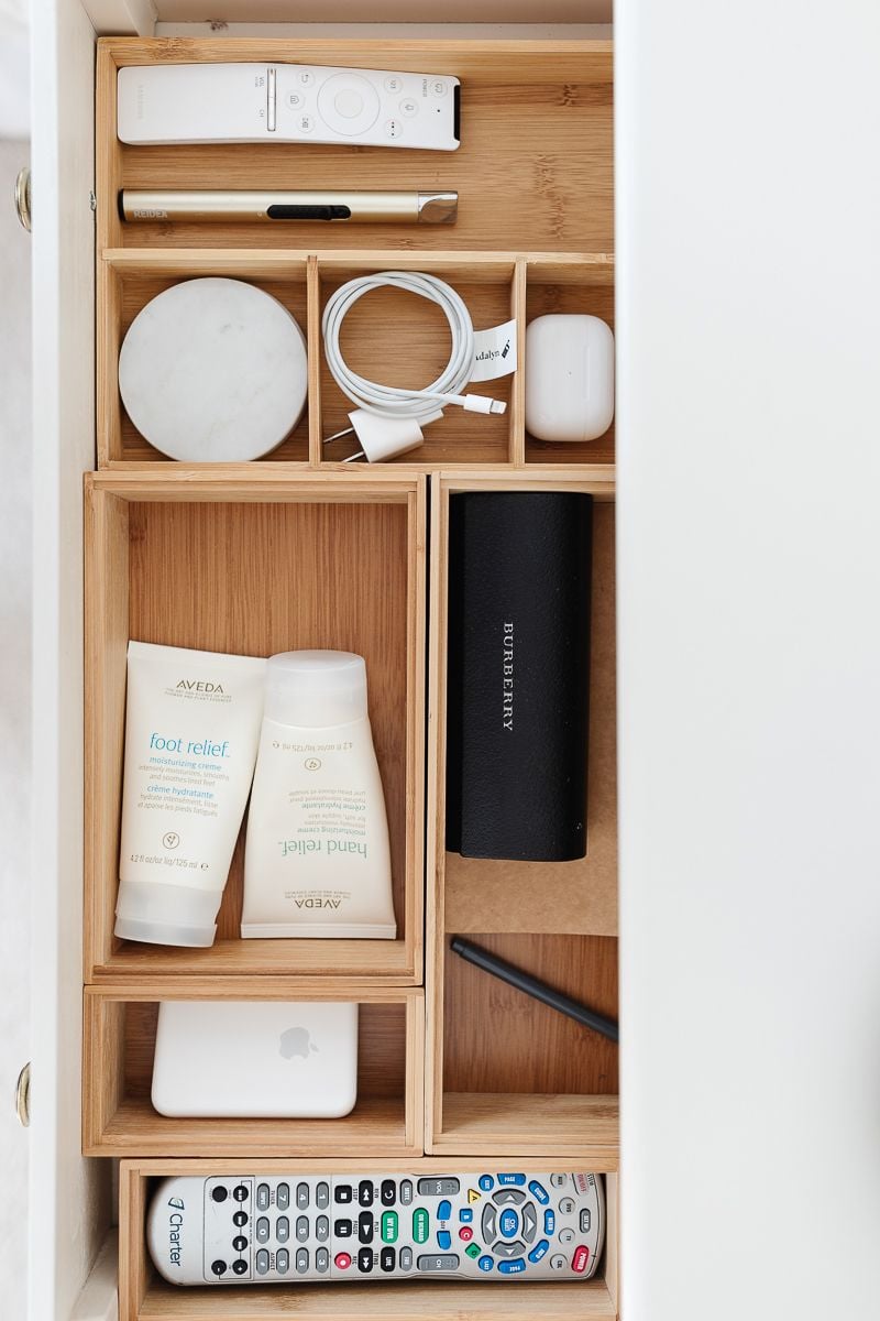 An open drawer with nightstand organization of remotes, lotions and more
