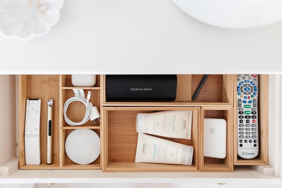 A drawer opened with nightstand organization of remotes, lotions and more