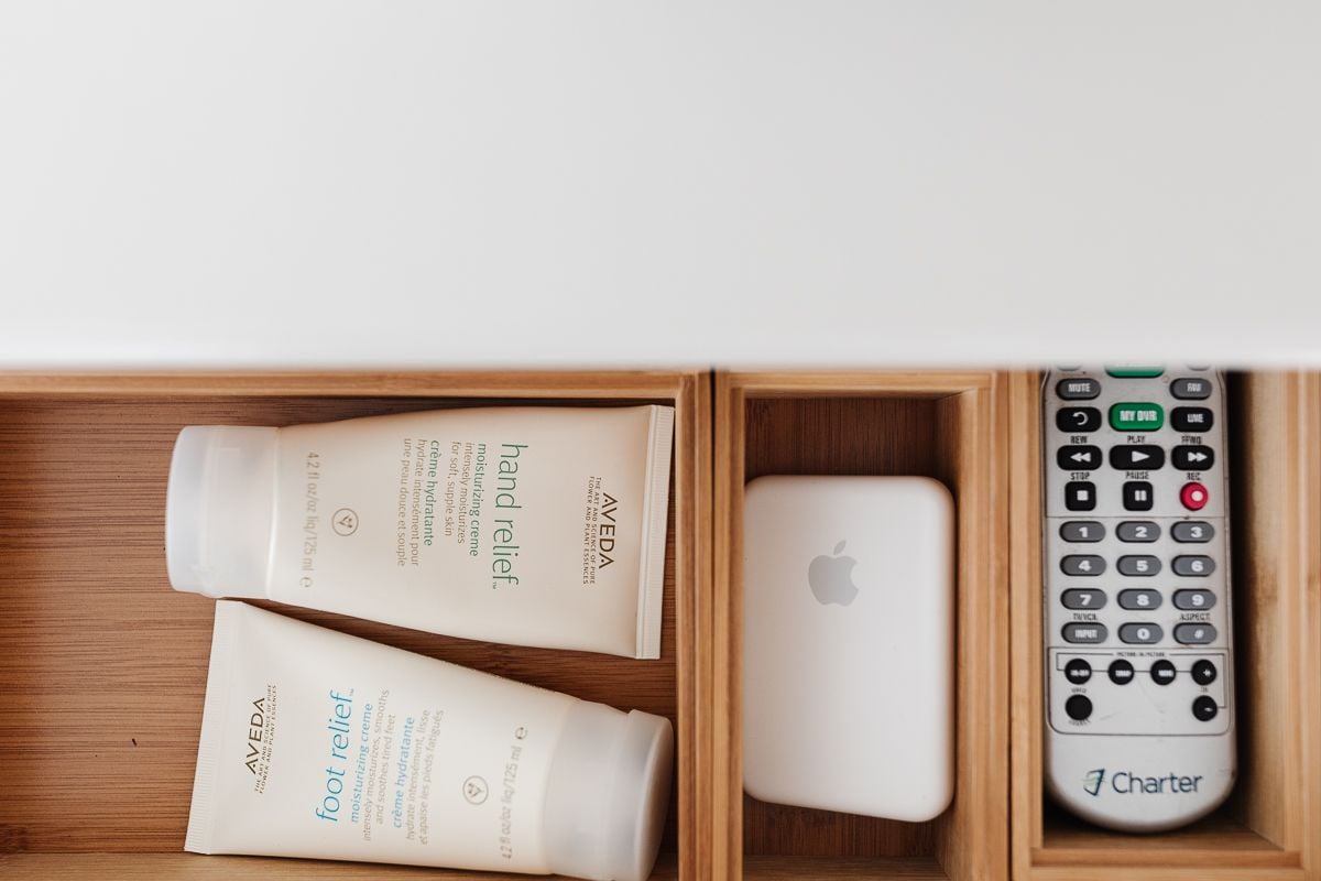 A drawer opened with nightstand organization of remotes, lotions and more