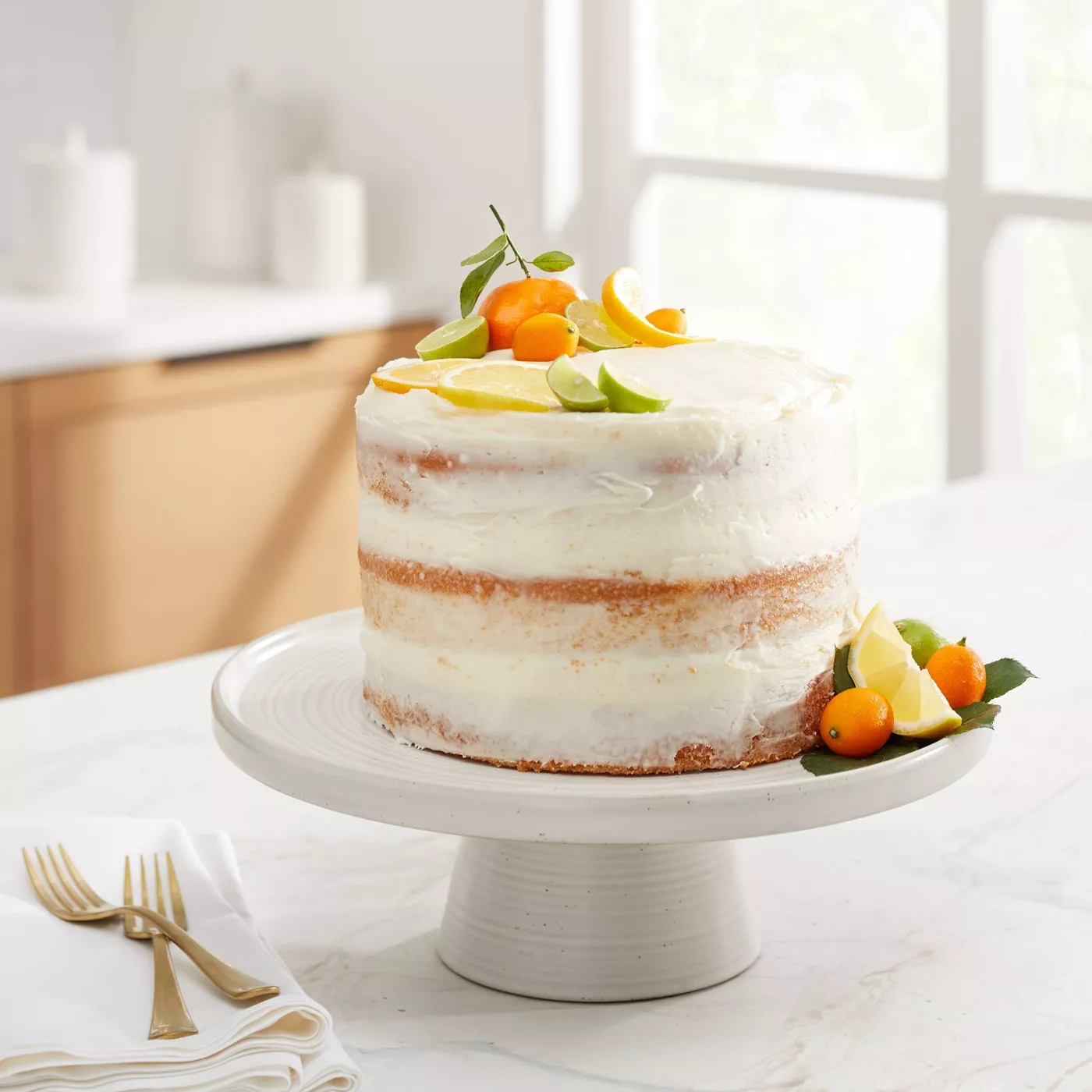 A citrus cake on a white cake stand in a home kitchen