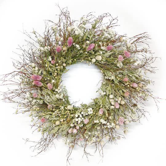 A circular wreath made of dried branches, green leaves, and pink and white flowers on a white background captures the essence of spring wreaths beautifully.