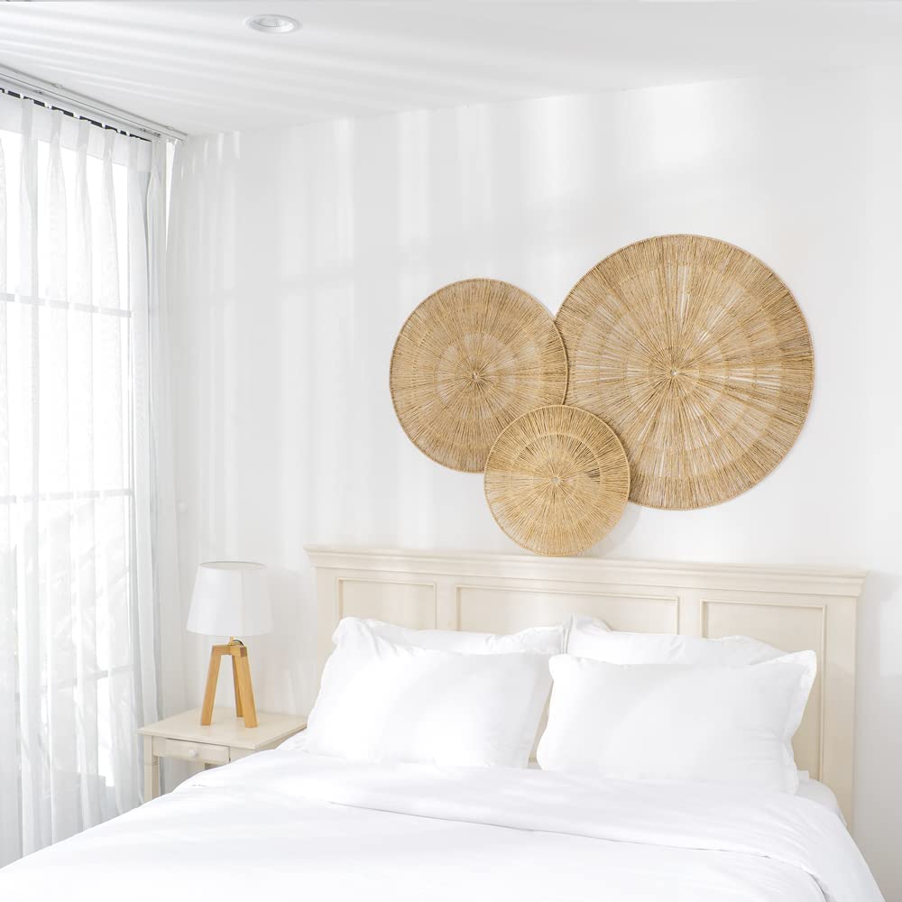 A white bedroom with three seagrass wall circles hung as art over bed