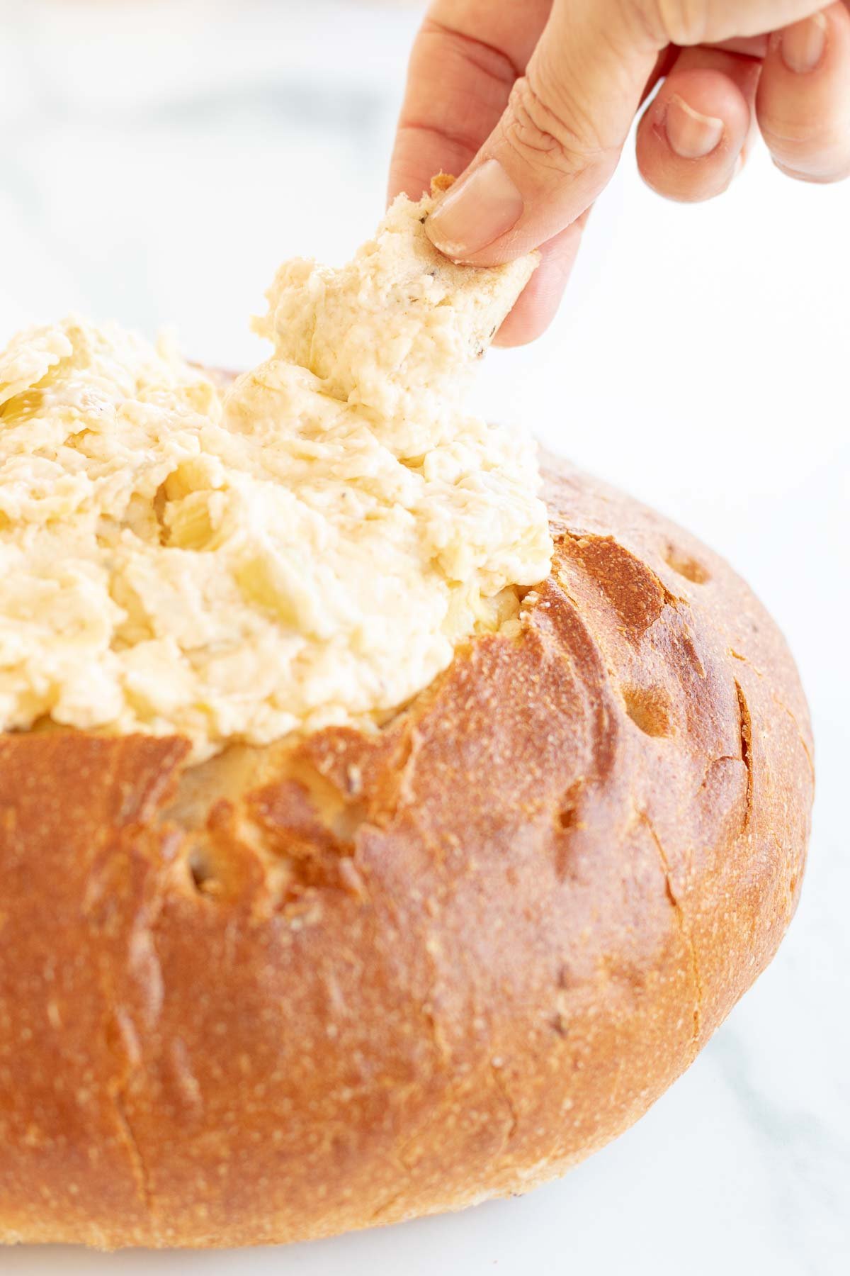 dipping into artichoke dip in bread bowl