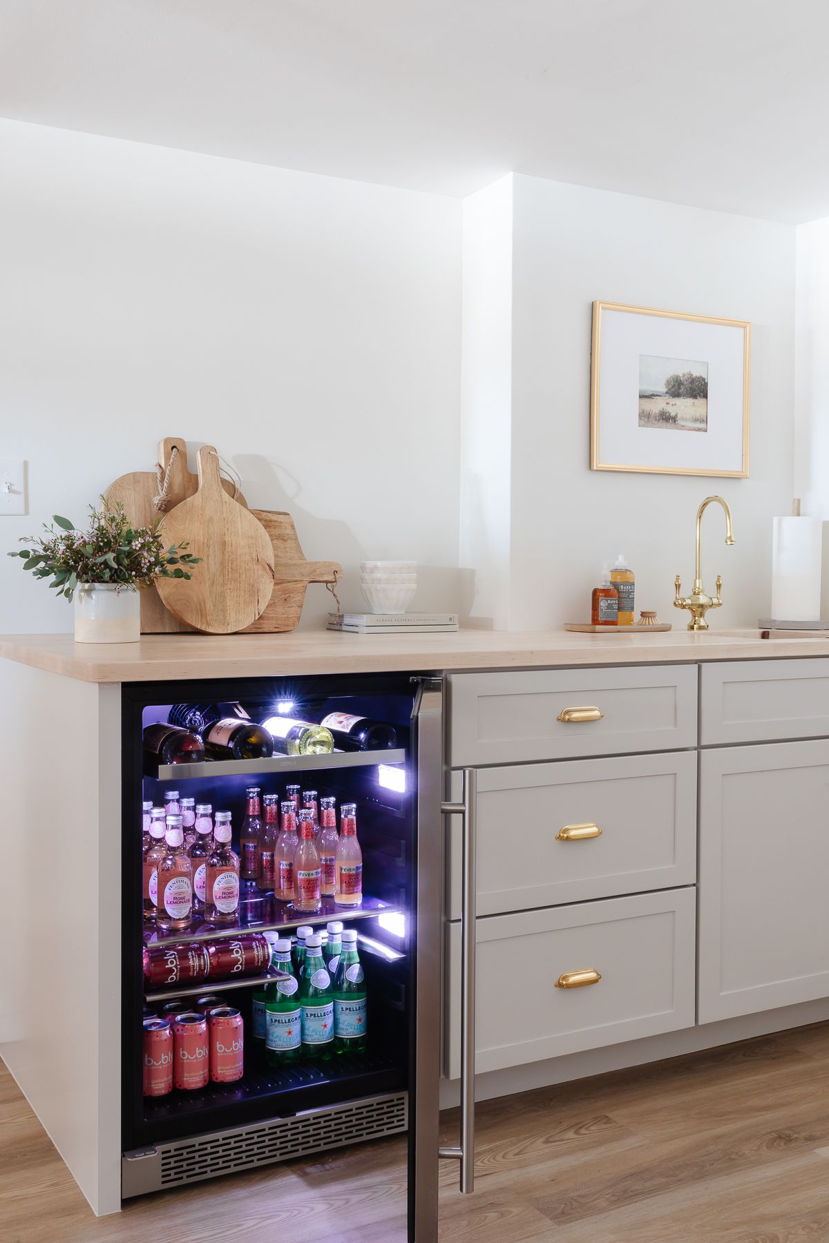 A basement bar with gray cabinetry and a beverage cooler.