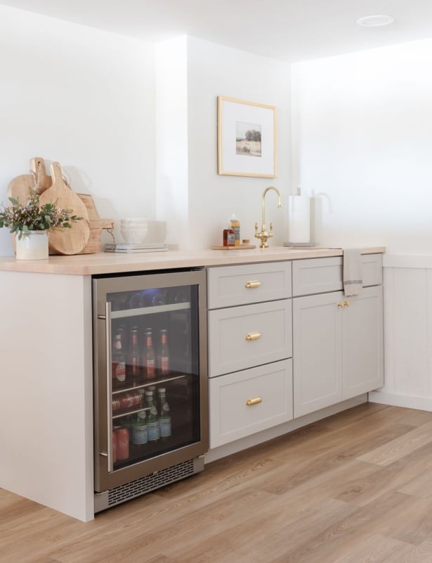 A basement bar with gray cabinets and butcher block countertops
