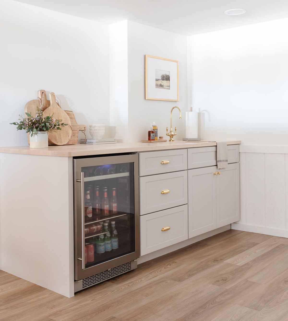 A basement bar with gray cabinets and butcher block countertops