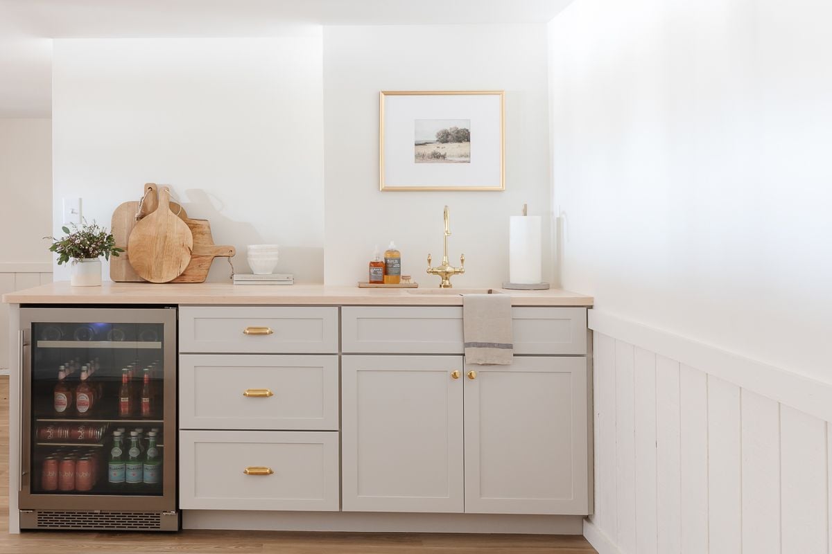 A basement bar with gray cabinets and butcher block countertops