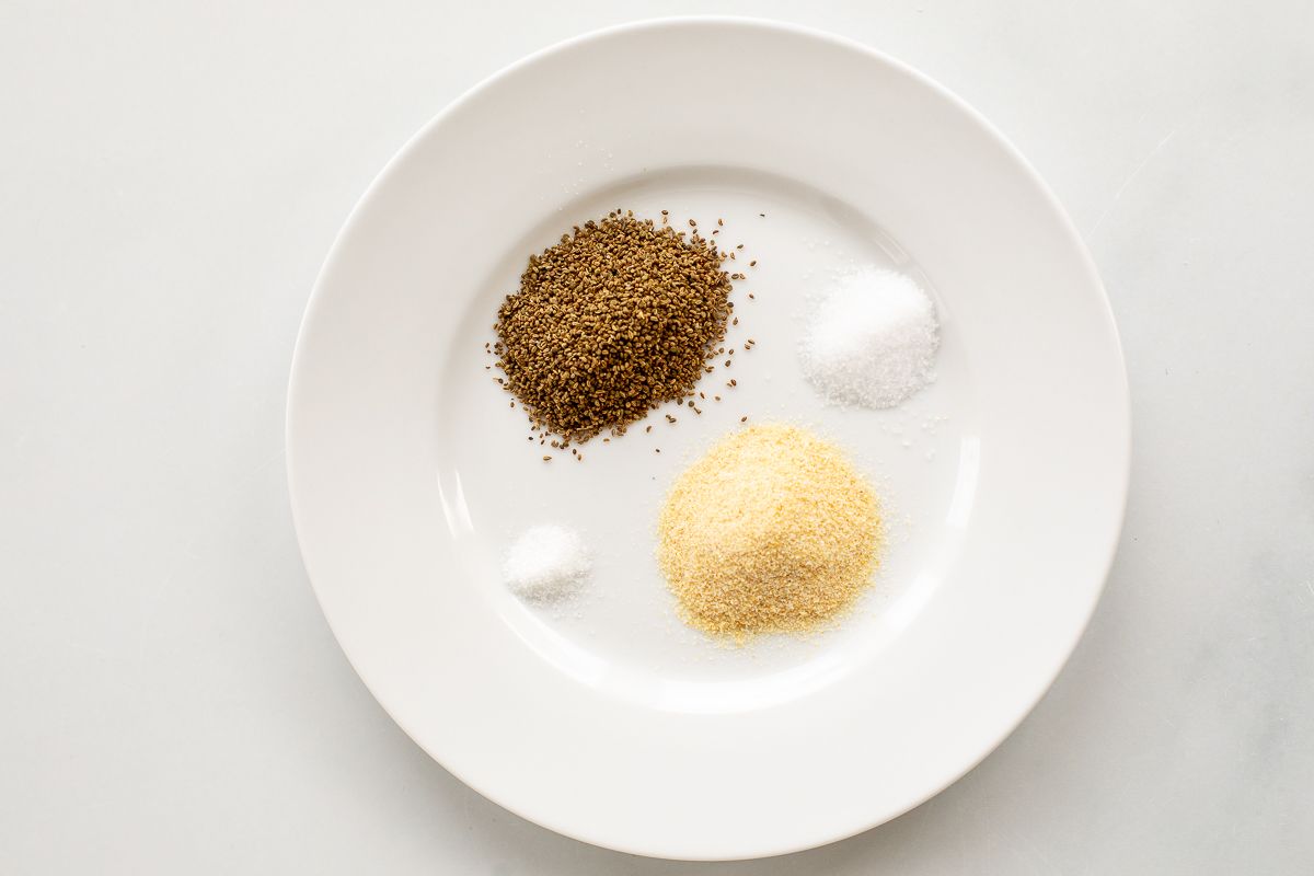 A white plate with four small piles of spices for a beau monde seasoning recipe.