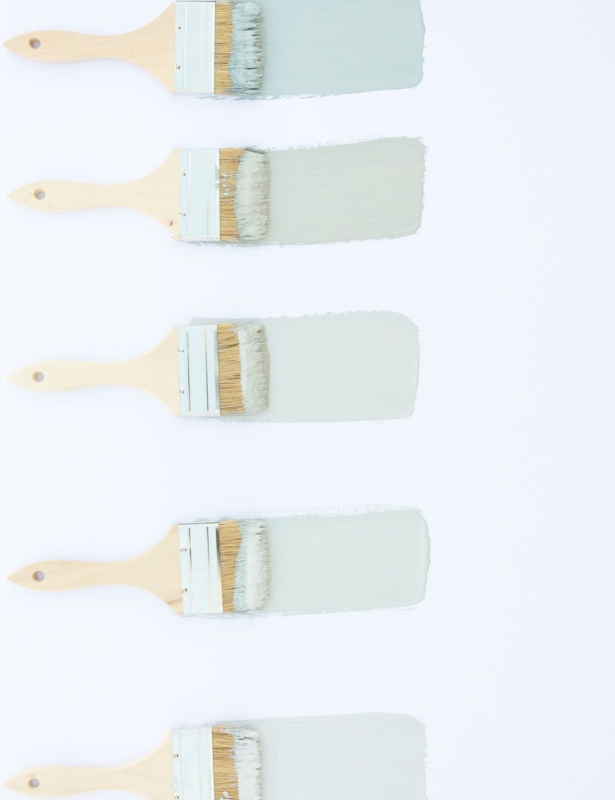 5 paint brushes laid out on a white surface, with samples of blue gray paint colors