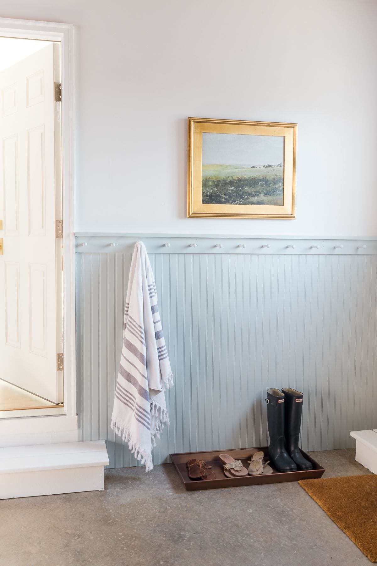 A beadboard mudroom area in a garage, painted in the blue gray paint color Smoke from Benjamin Moore