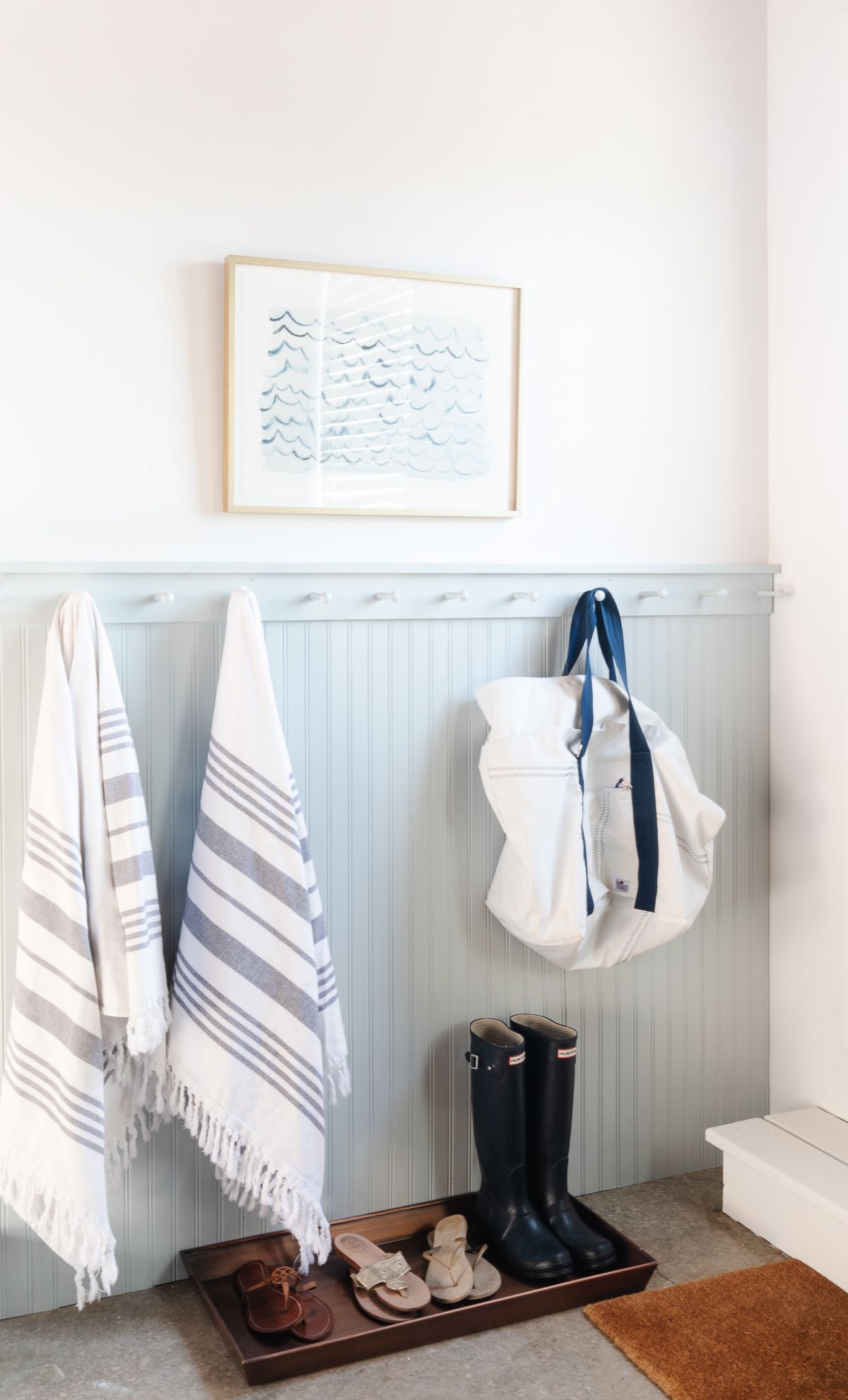 A beadboard mudroom area in a garage, painted in the blue gray paint color Smoke from Benjamin Moore