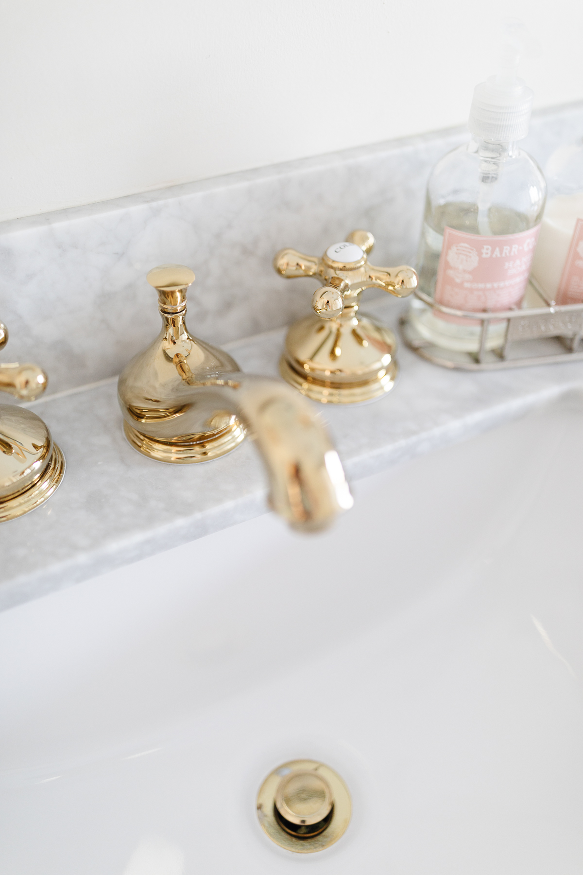 a bathroom sink with a brass faucet and soap dispenser.