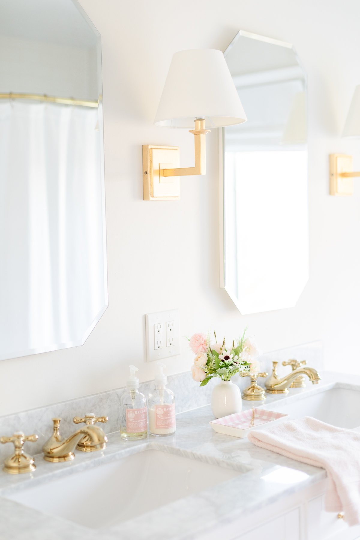 a bathroom with two brass faucets and two mirrors.