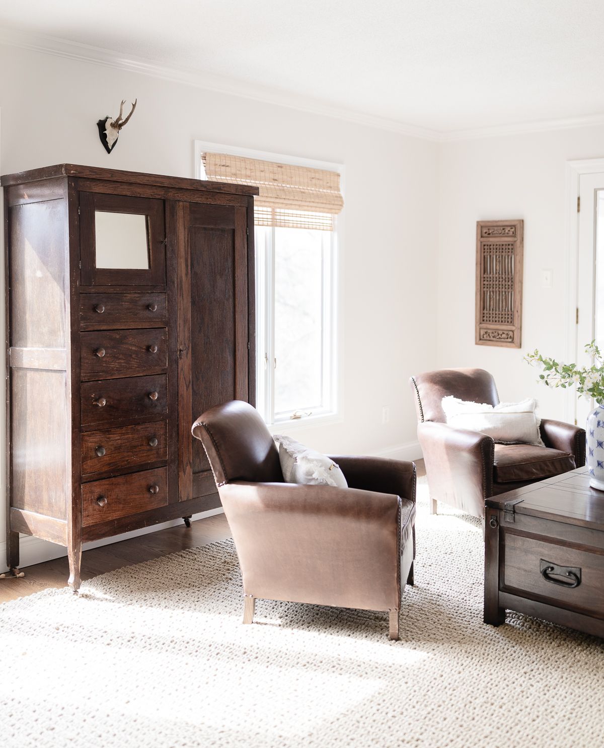 A living room in a cozy home, featuring leather chairs and an antique wood armoire