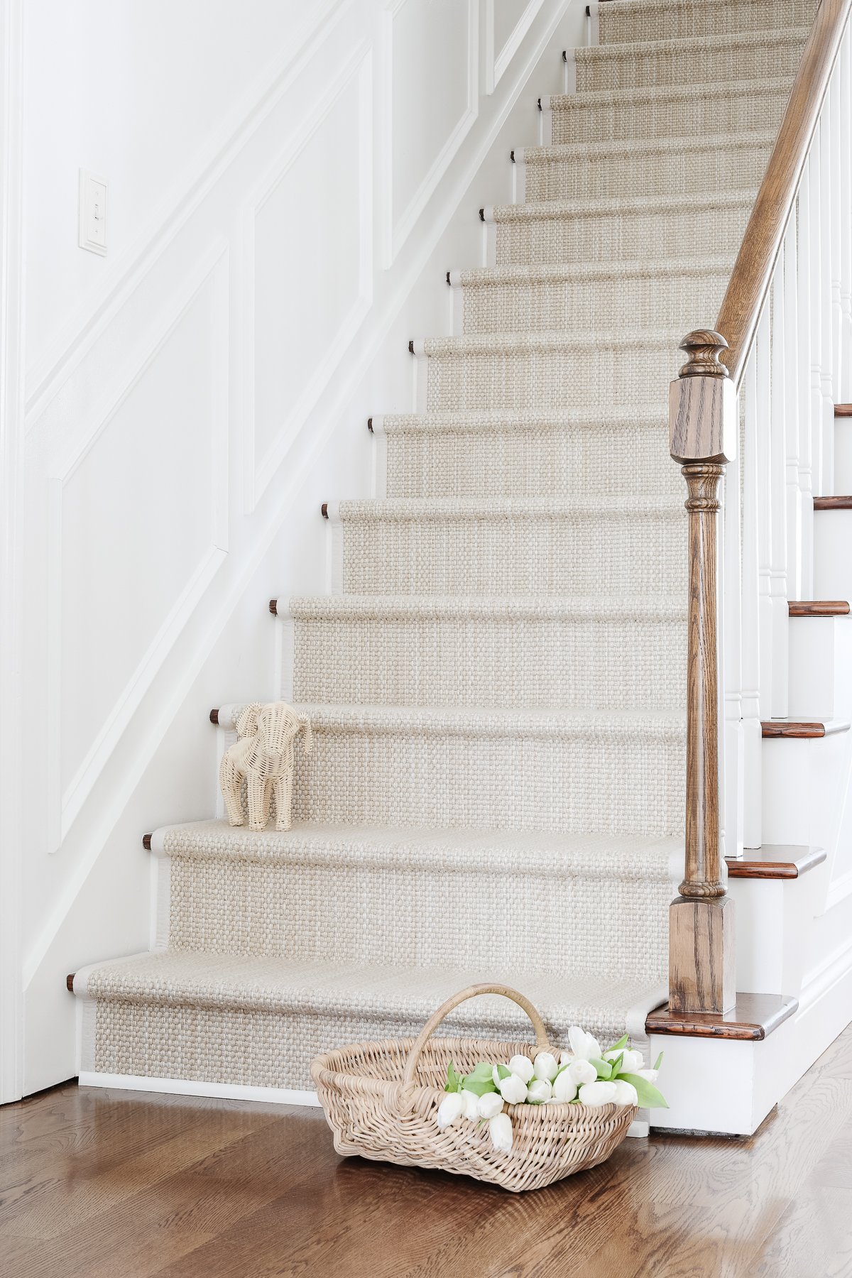 A diy stair runner in a soft neutral color, with a rattan puppy on a step.